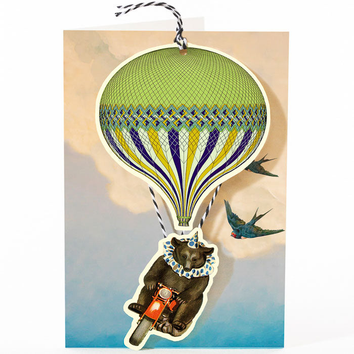 A whimsical Madame Treacle greeting card featuring a bear in clothing riding a Balloon and Bear Fandangle designed to look like an onion with a bird flying alongside.