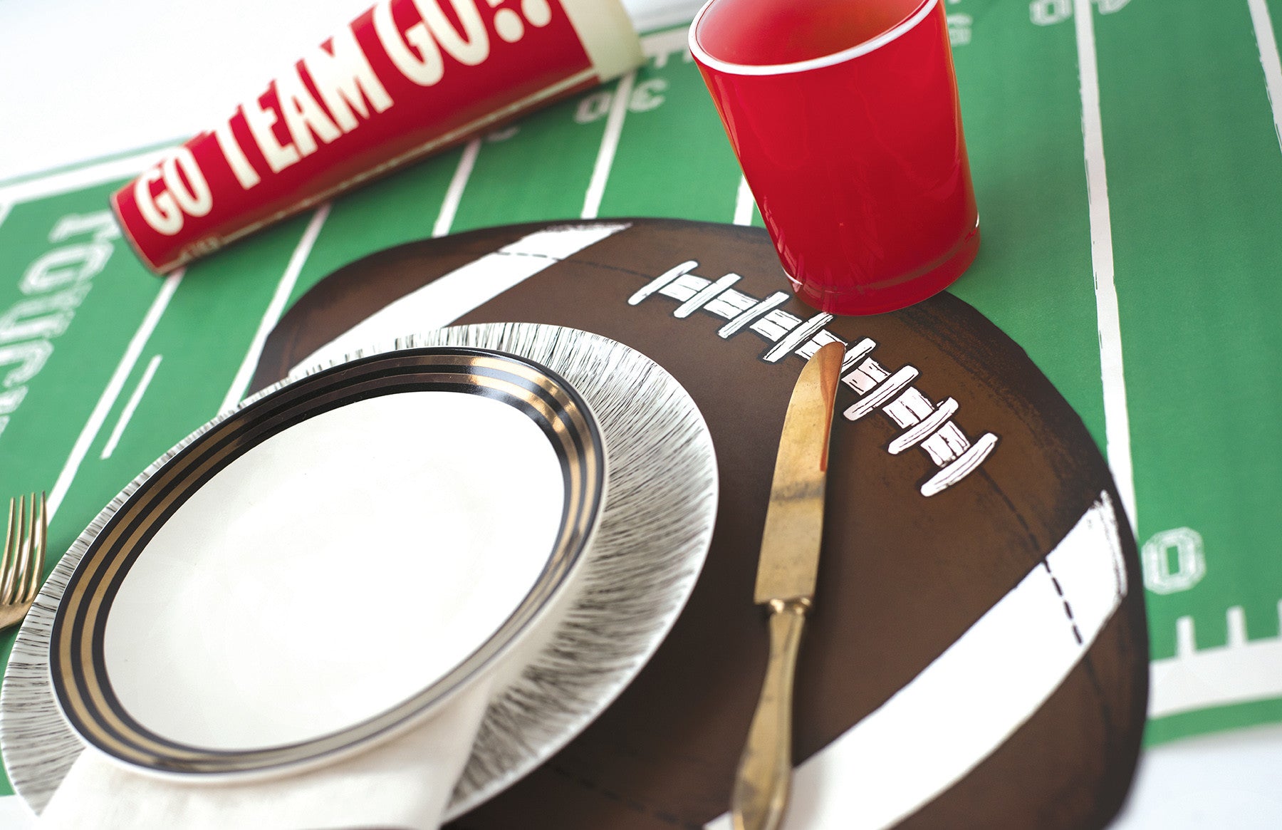 A tablescape with a football tablecloth and Hester &amp; Cook Die-cut Football Placemats.