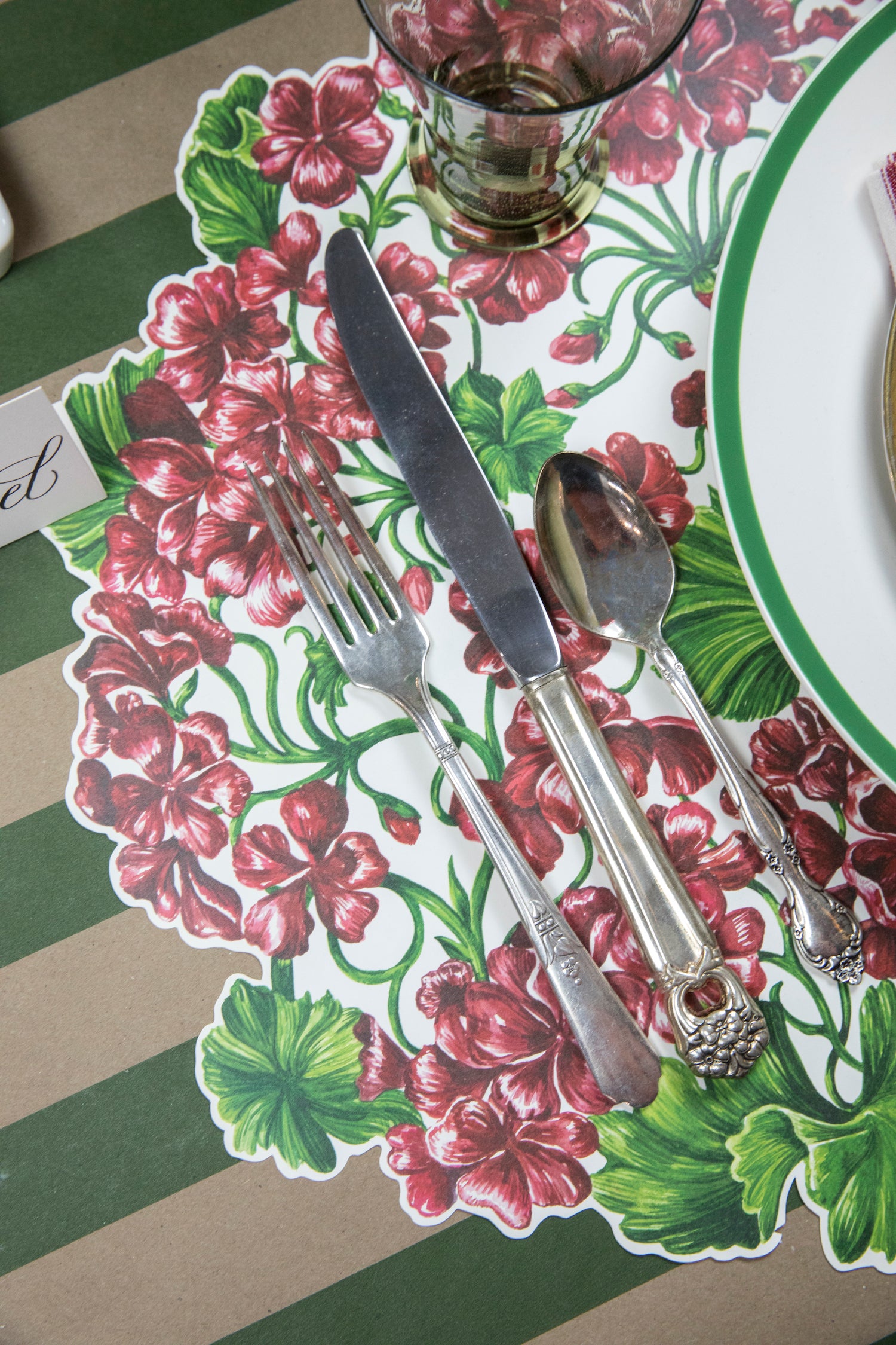 A table setting with a Hester &amp; Cook Die-Cut Geranium Placemat and silverware.