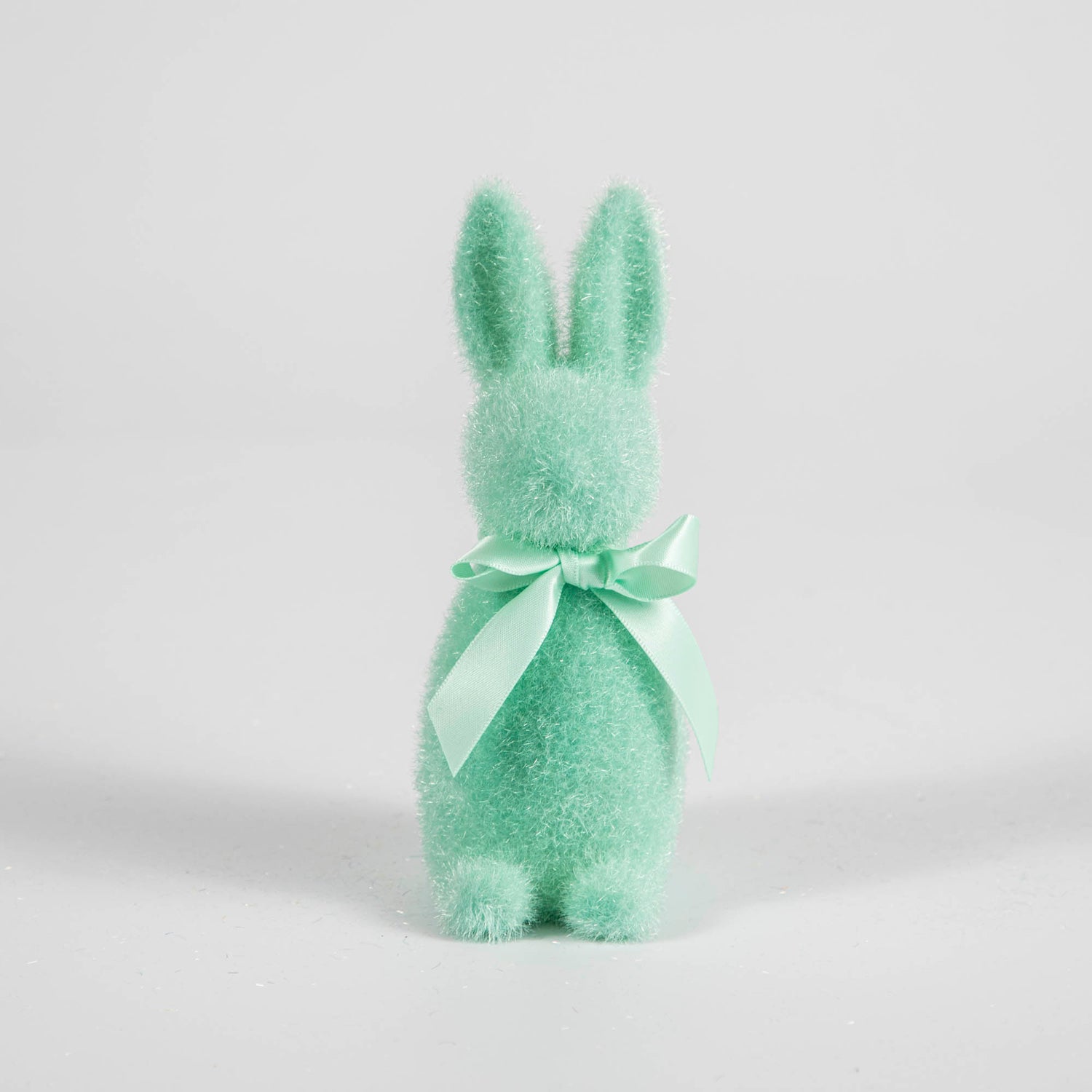 A Small Flocked Pastel Button Nose Bunny from Glitterville with a bow on a white backround.
