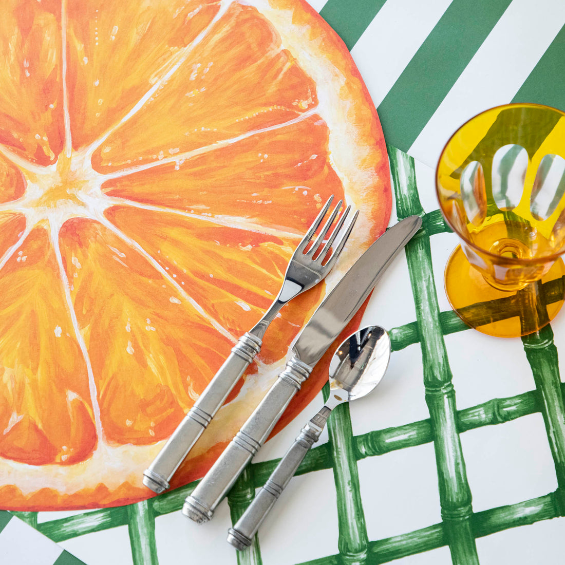 A plate with a slice of orange on a Green Lattice placemat by Hester &amp; Cook.