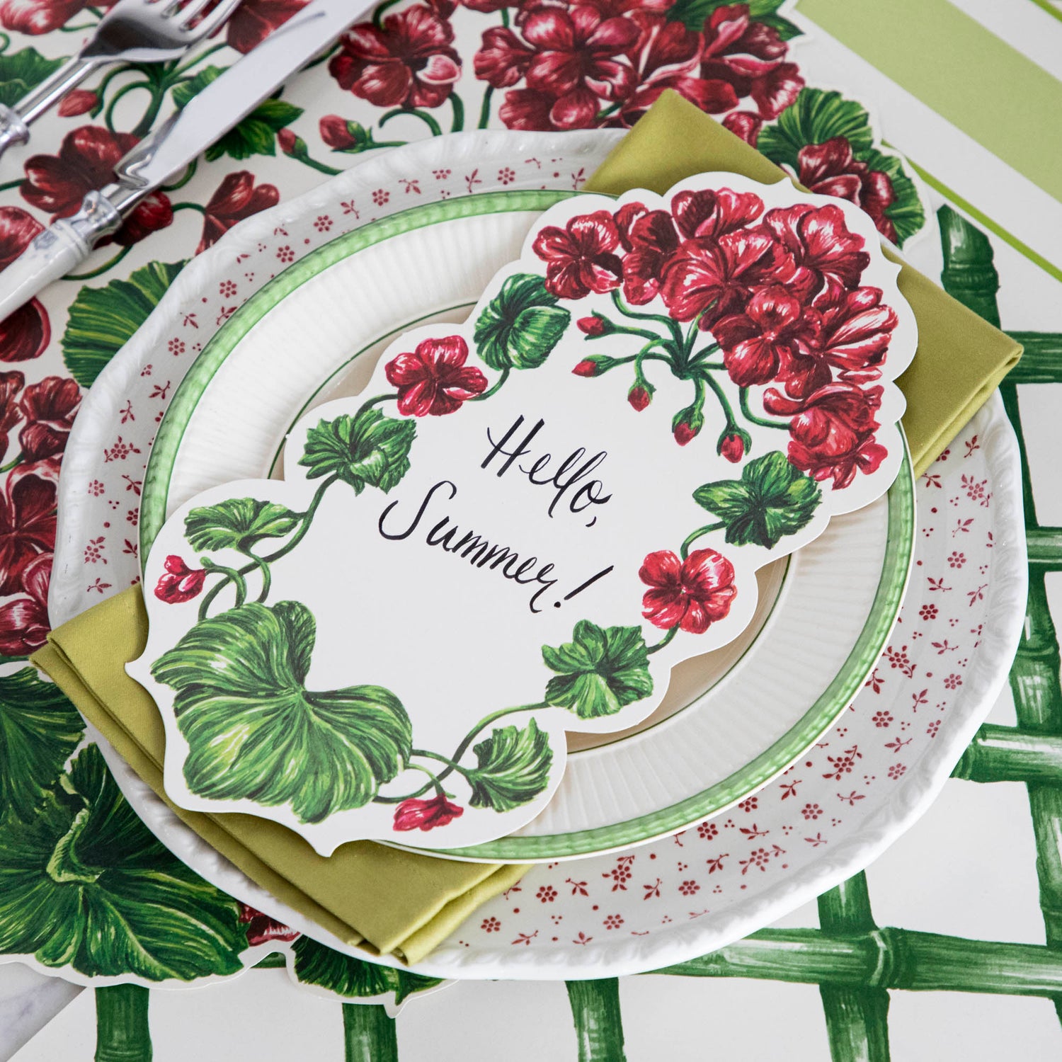A Geranium Table Accent with &quot;Hello Summer!&quot; written on it resting on the plate of an elegant place setting.