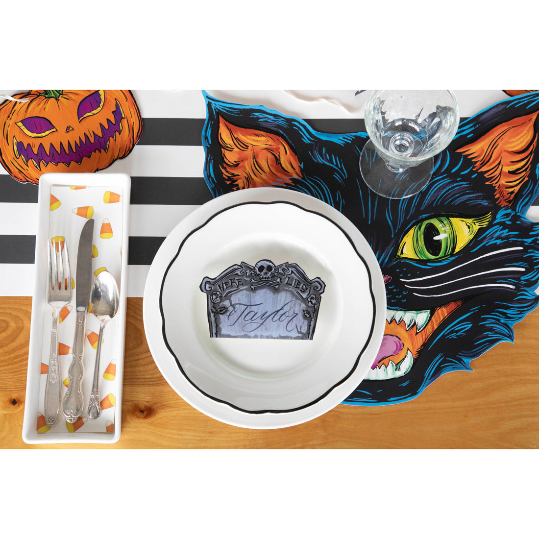 Top-down view of a spooky Halloween place setting featuring a Tombstone Place Card labeled &quot;Taylor&quot; resting on the plate.