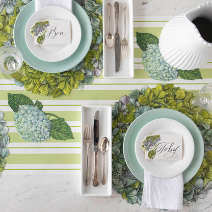 A table set with plates and silverware adorned by a stunning Hester &amp; Cook Die-Cut Hydrangea Placemat, creating an enchanting tablescapes with its antique coloring.