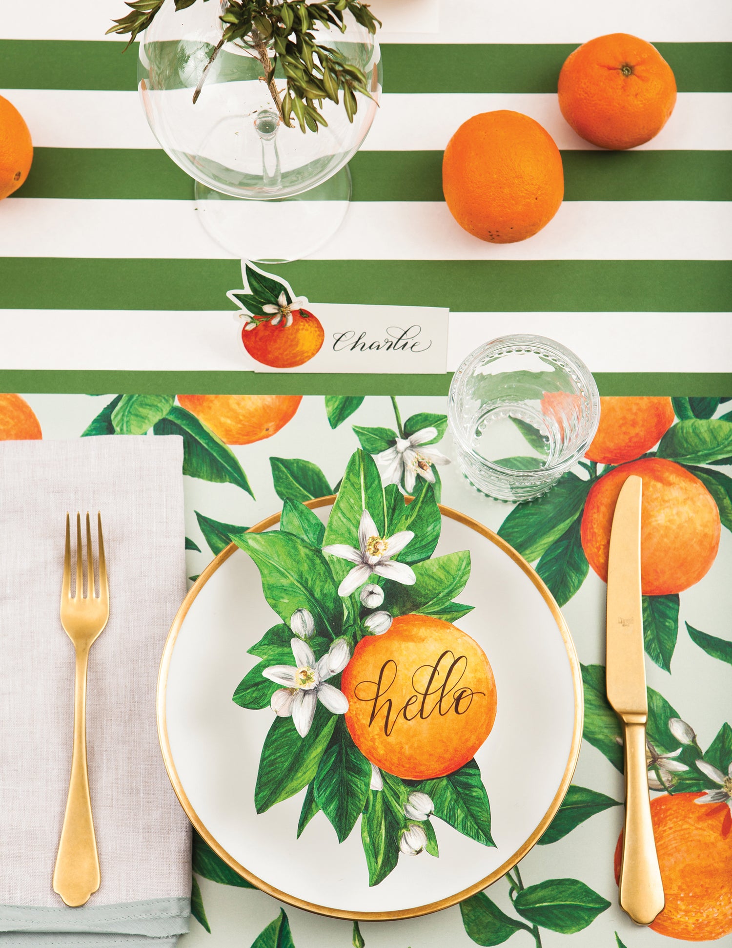 A vibrant table setting with Dark Green Classic Stripe Runner by Hester &amp; Cook, oranges, and a fork, perfect for entertaining.