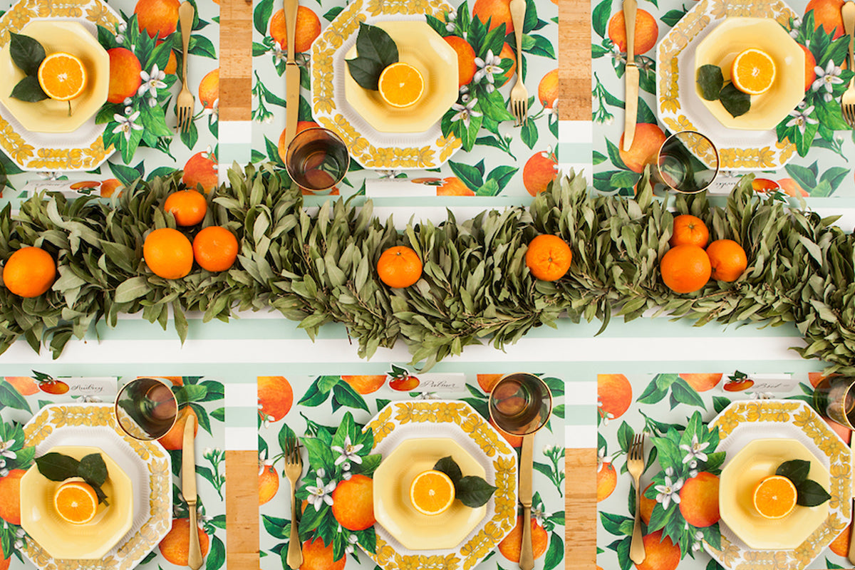 The Orange Orchard Placemat used under an elegant citrus-themed table setting for six, from above.