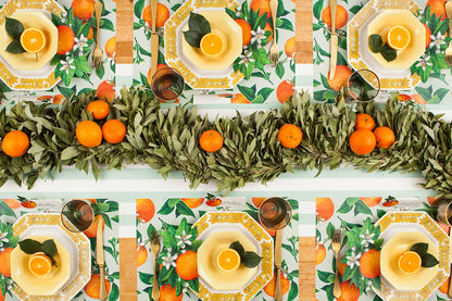 The Orange Orchard Placemat used under an elegant citrus-themed table setting for six, from above.