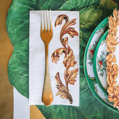 A party table setting with a fork on a Gold Flora Napkin from Hester &amp; Cook next to plates.