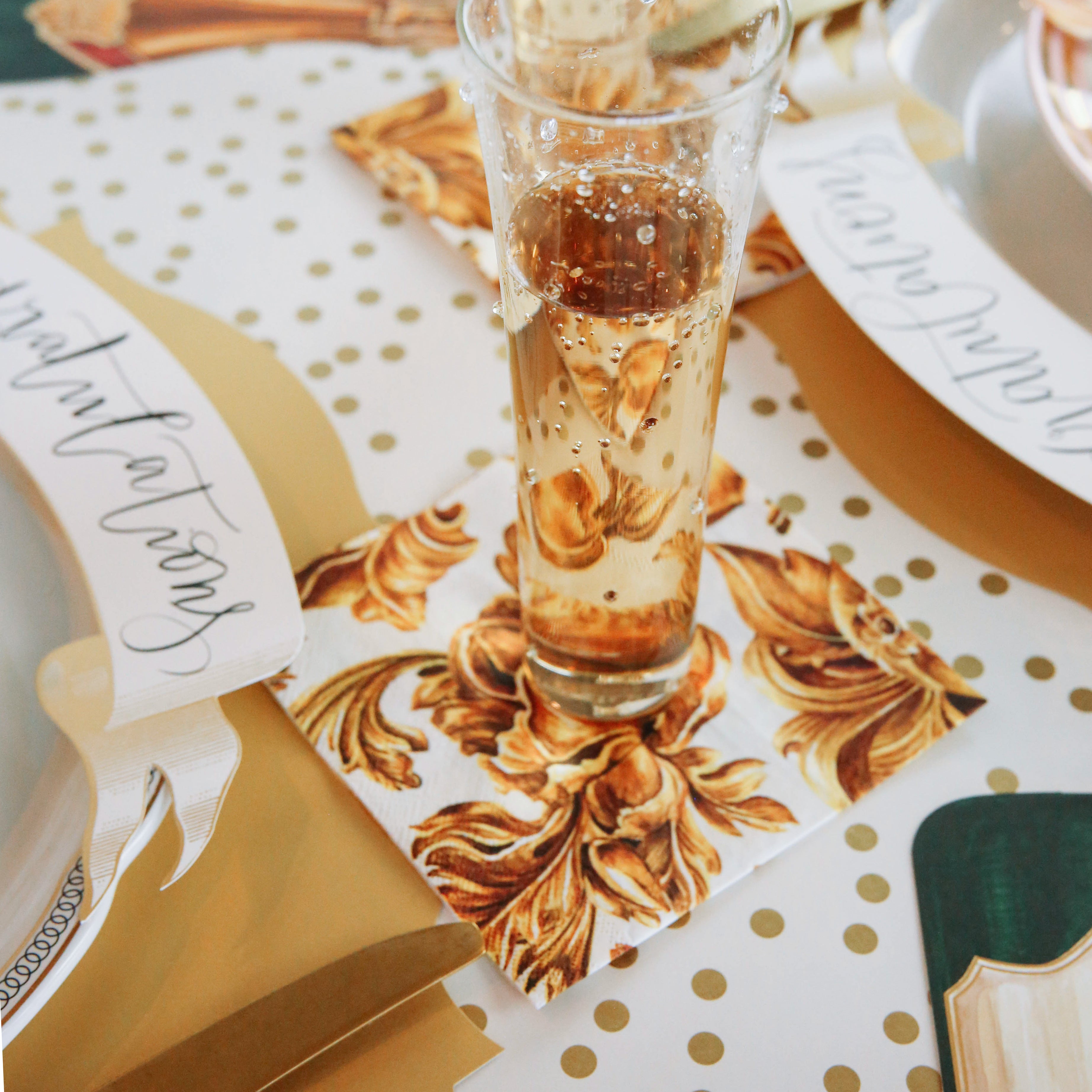 A glass of Gold Flora Napkins champagne on a table setting by Hester &amp; Cook.