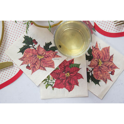 Poinsettia napkins with flowers on them and a glass of liquid on a table, made in Germany, by Hester &amp; Cook.