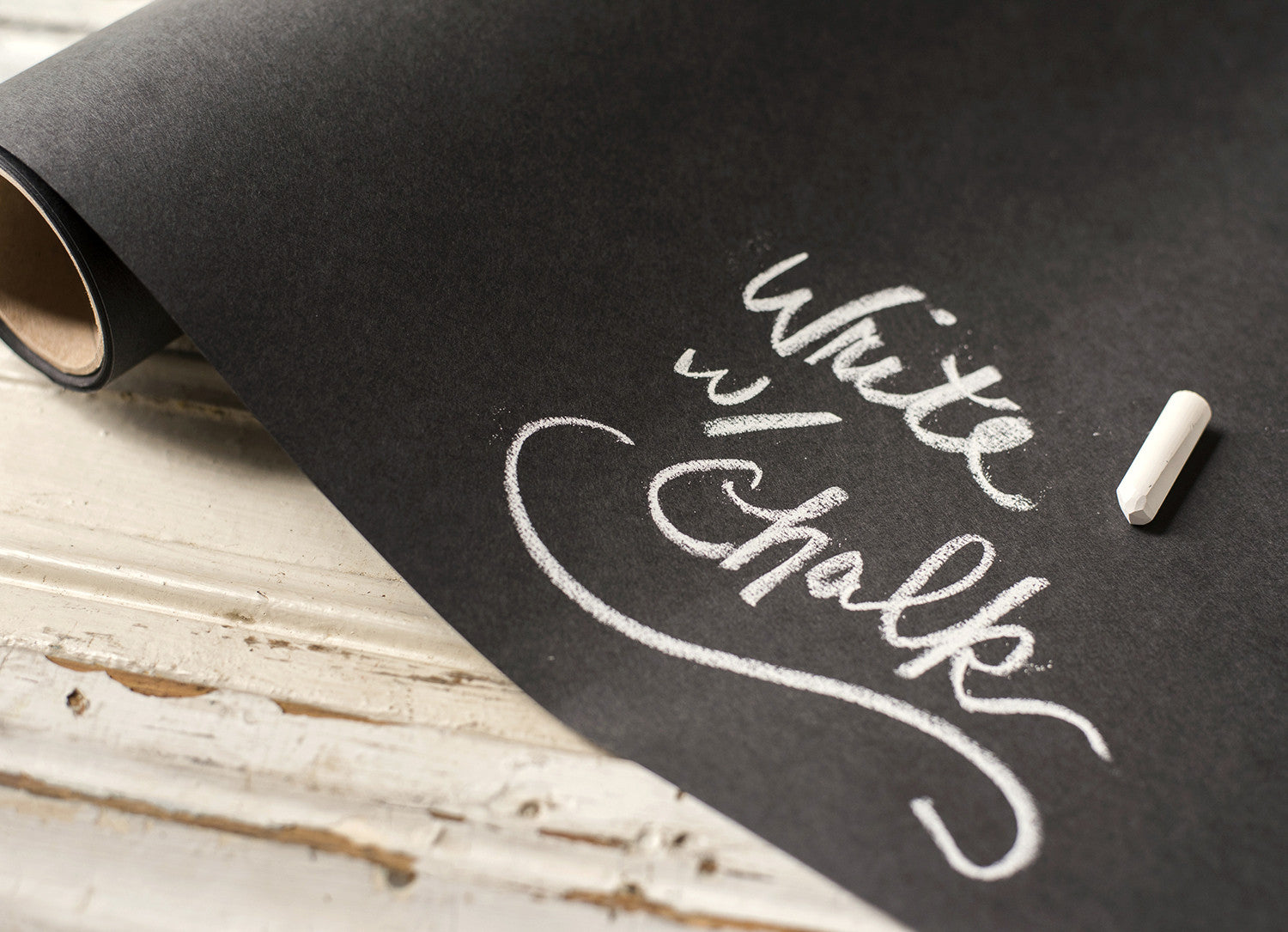 Close-up of the Chalkboard Runner roll, with a piece of chalk and handwritten note: &quot;Write w/ Chalk&quot;.