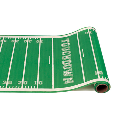 A paper runner roll in green and white, resembling a football field complete with numbered yard lines and end zone with the word &quot;TOUCHDOWN&quot;, repeating in a pattern down the length of the roll.