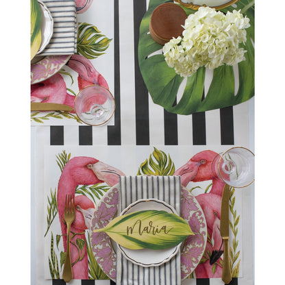 Elegant Hester &amp; Cook Die-cut Monstera Placemat place setting with pink flowers and a black and white striped tablecloth.