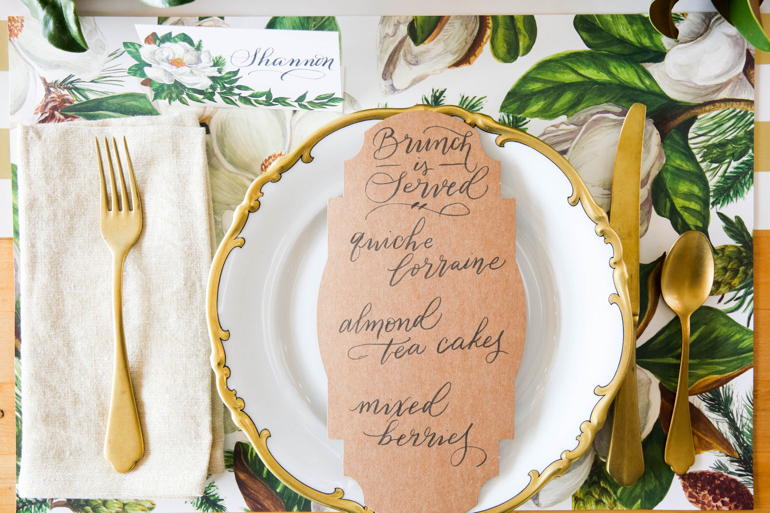 An elegant floral place setting featuring a Kraft Frame Table Accent with a menu hand-written in beautiful script.