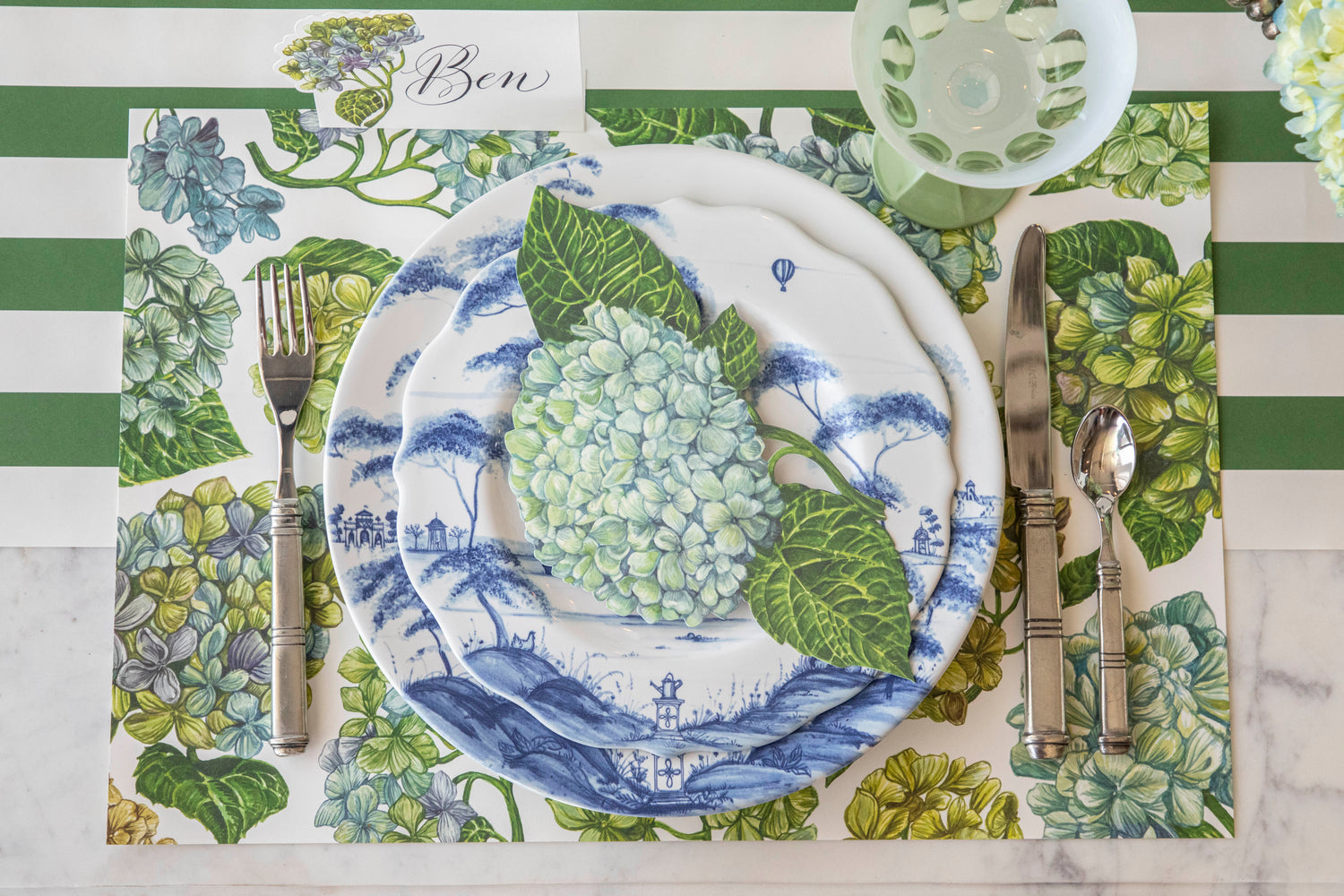 An elegant experience of dining with a plate adorned with silverware and placed on a Hester &amp; Cook Blooming Hydrangeas Placemat.