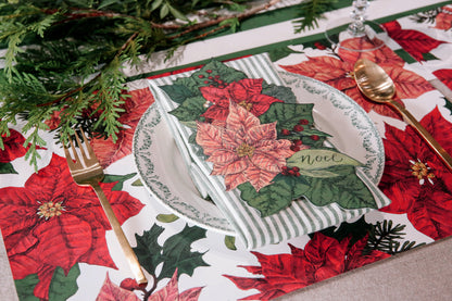 The Festive Poinsettias Placemat under an elegant winter-themed place setting.