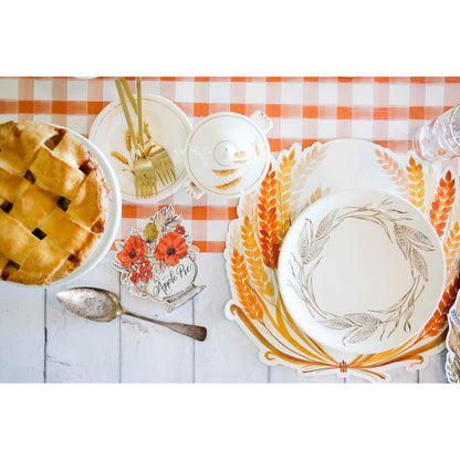 Thanksgiving table setting with Die-cut Golden Harvest placemats by Hester &amp; Cook and orange and white plates and silverware.