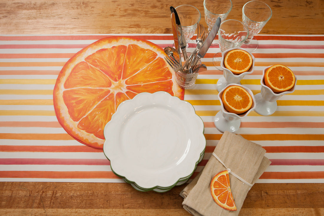 A table with plates and glasses, adorned with an elegant napkin showcasing juicy Hester &amp; Cook Orange Slice Gift Tags.