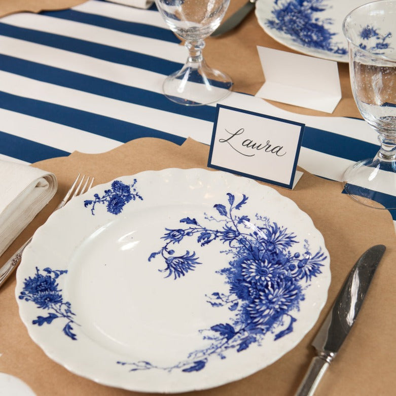 A table setting with Hester &amp; Cook navy frame place cards and blue and white plates and napkins for guests.
