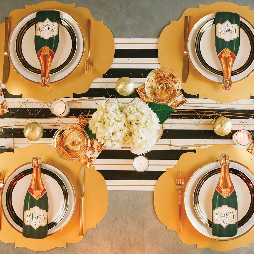 Top-down view of an elegant table setting for four featuring a Champagne Table Accent resting on each plate.