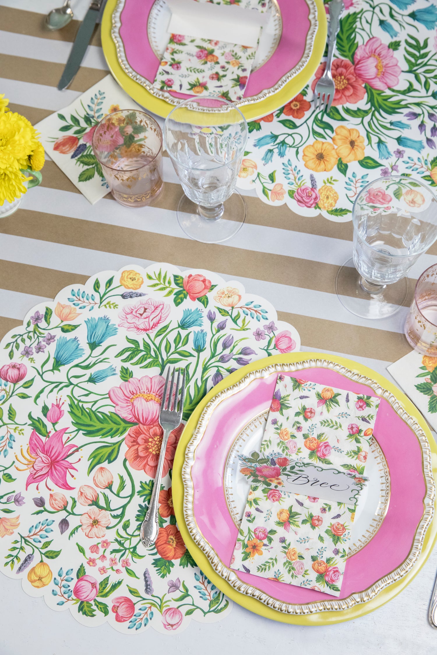 A pink and yellow table setting with a Kraft White Classic Stripe Runner by Hester &amp; Cook, perfect for entertaining.