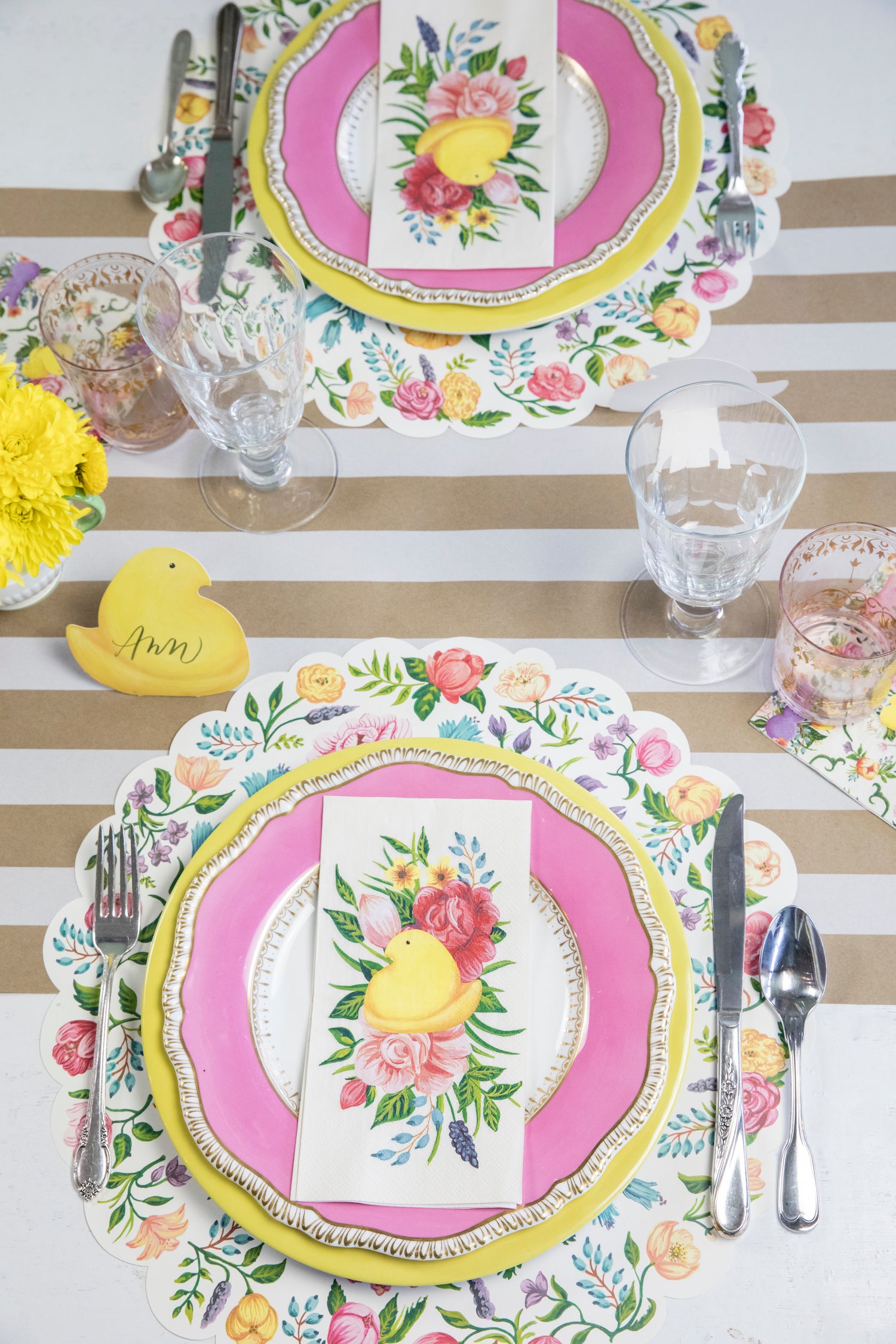 A table setting with pink and yellow plates and napkins, featuring the Hester &amp; Cook Kraft White Classic Stripe Runner, perfect for entertaining.