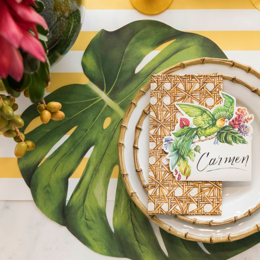 An elegant table setting adorned with tropical Die-cut Monstera Placemats from Hester &amp; Cook, complemented by colorful flowers.