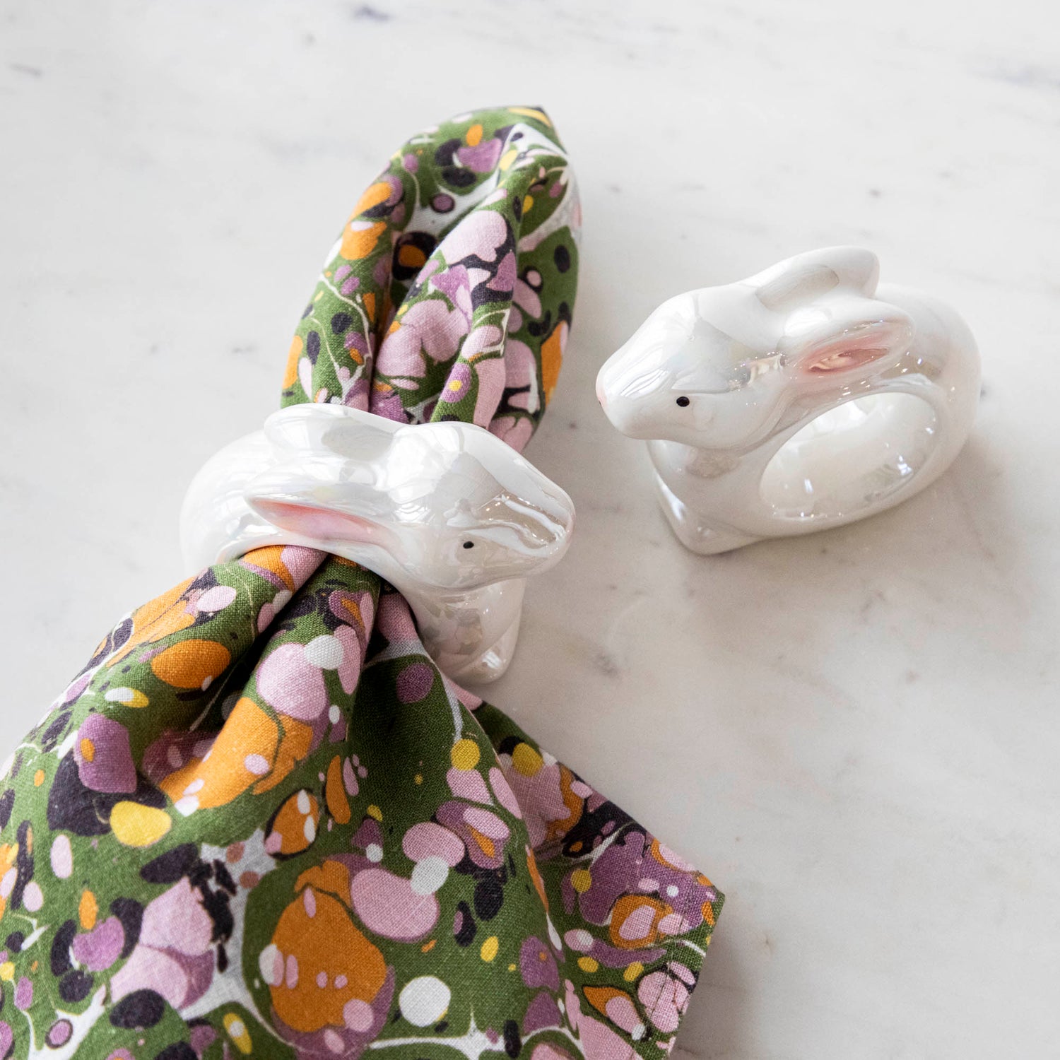 Two Glitterville Bunny Napkin Rings with a springy touch on a napkin.