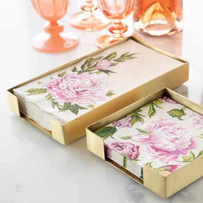 Two Brass Napkin Holders, guest-sized and cocktail-sized, containing pink floral napkins on a white table.