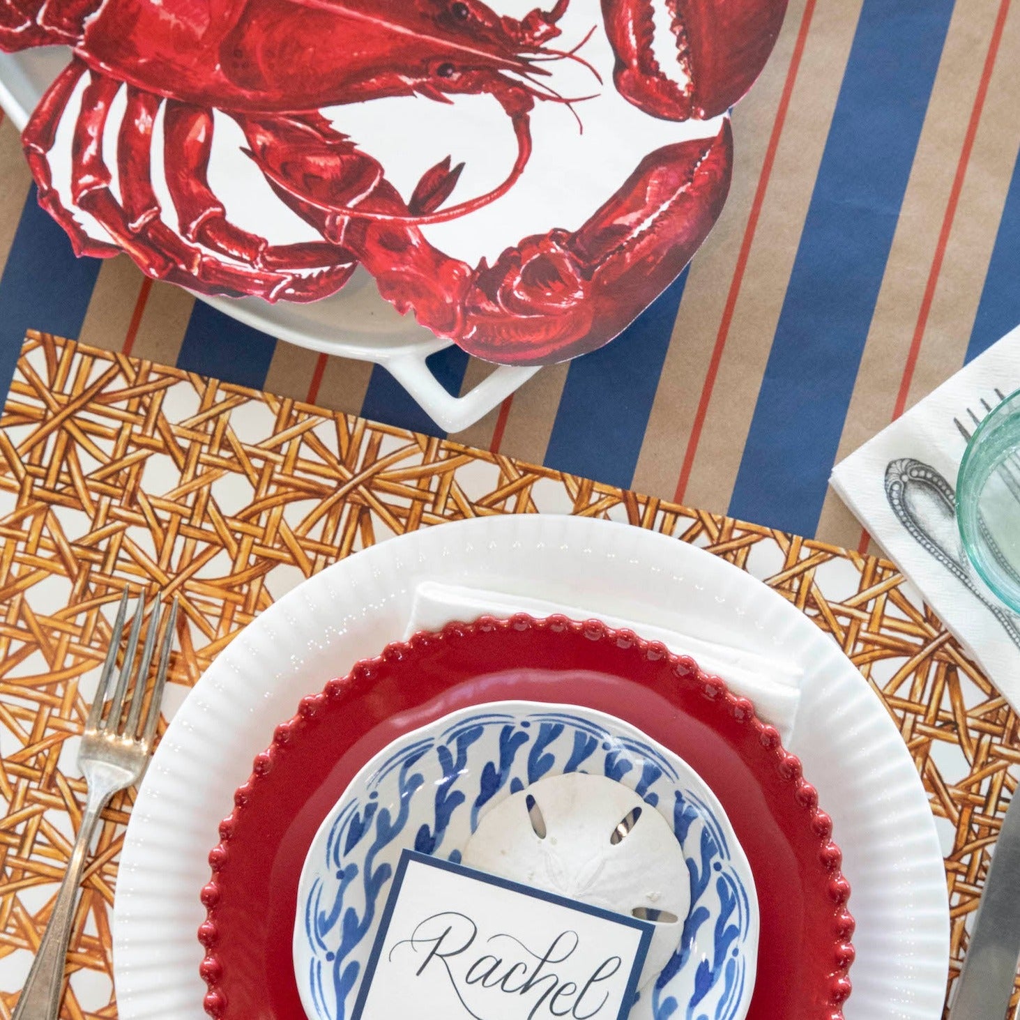 A red, white and blue table setting with a Hester &amp; Cook Rattan Weave Placemat.