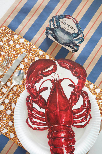 A table setting with a lobster and a Hester &amp; Cook Kraft Navy &amp; Red Awning Stripe Runner on it.