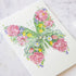 Artistic Butterfly Card created with floral patterns on a cream-colored high-quality card, accompanied by drawing materials on a dark surface by The DM Collection.