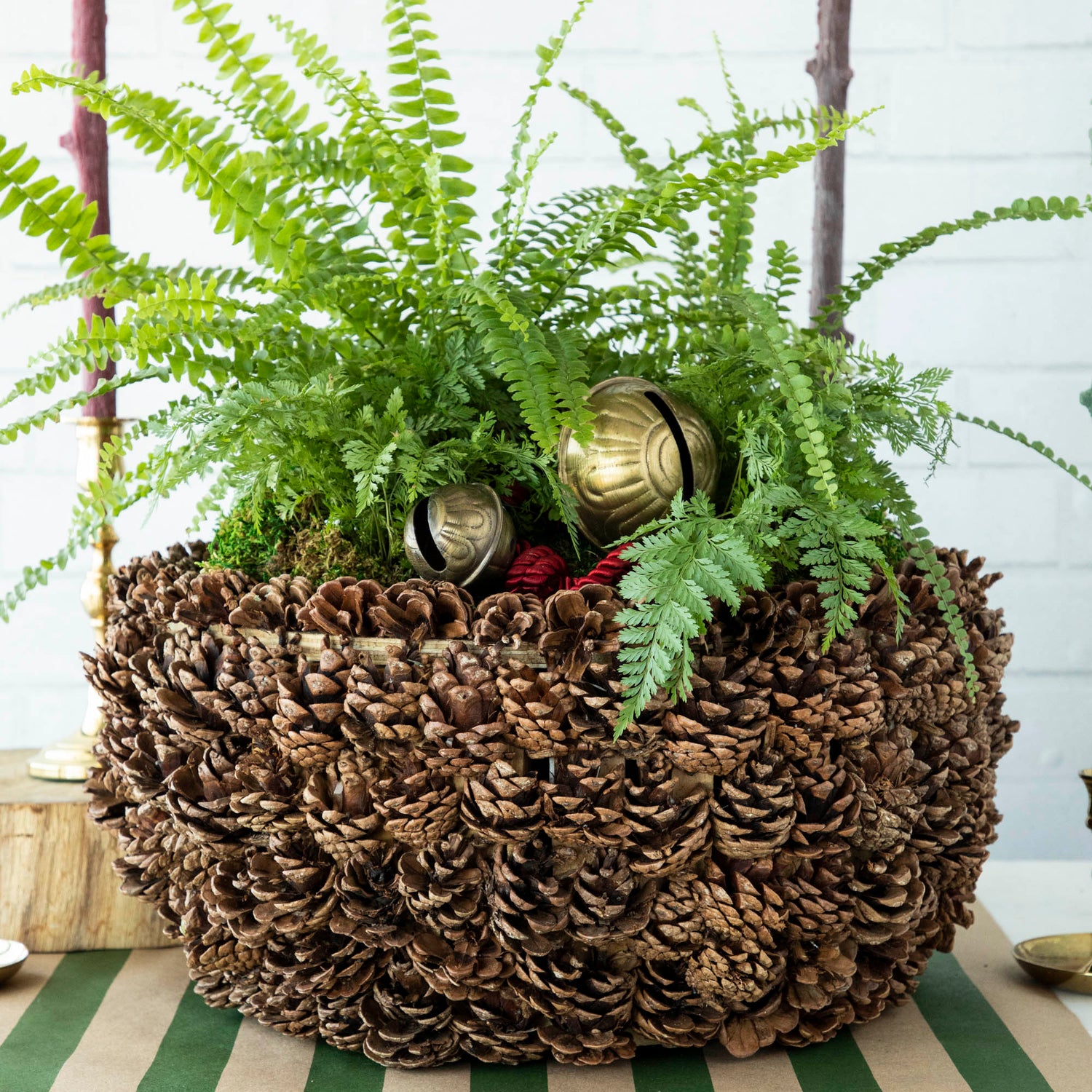 A Large Pinecone Bowl filled with greenery and ornaments, on a table.