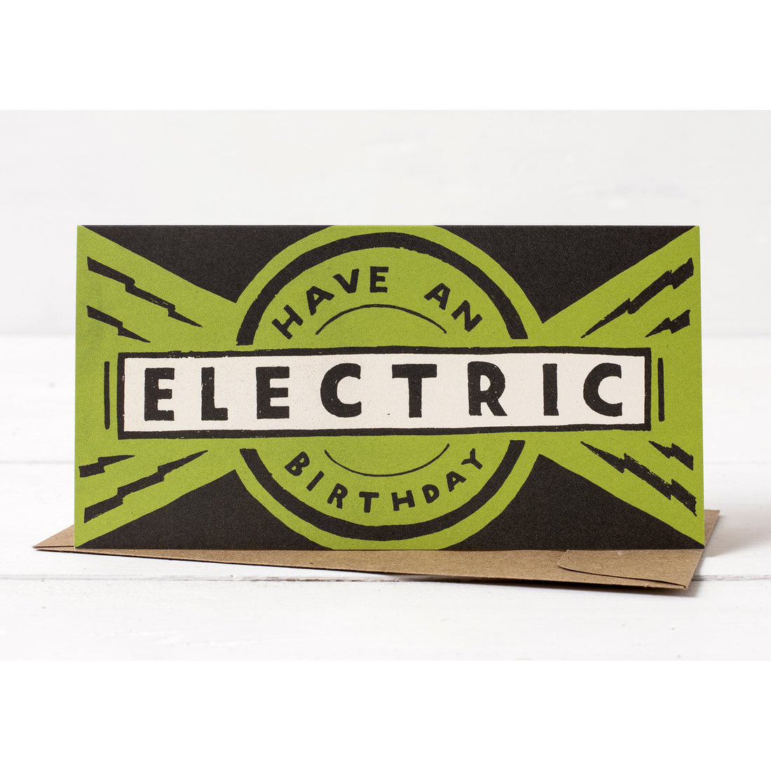 A Hester &amp; Cook birthday card with the phrase &quot;Have an Electric Birthday&quot; styled in bold, retro, hand-lettered font against a green and black starburst background.