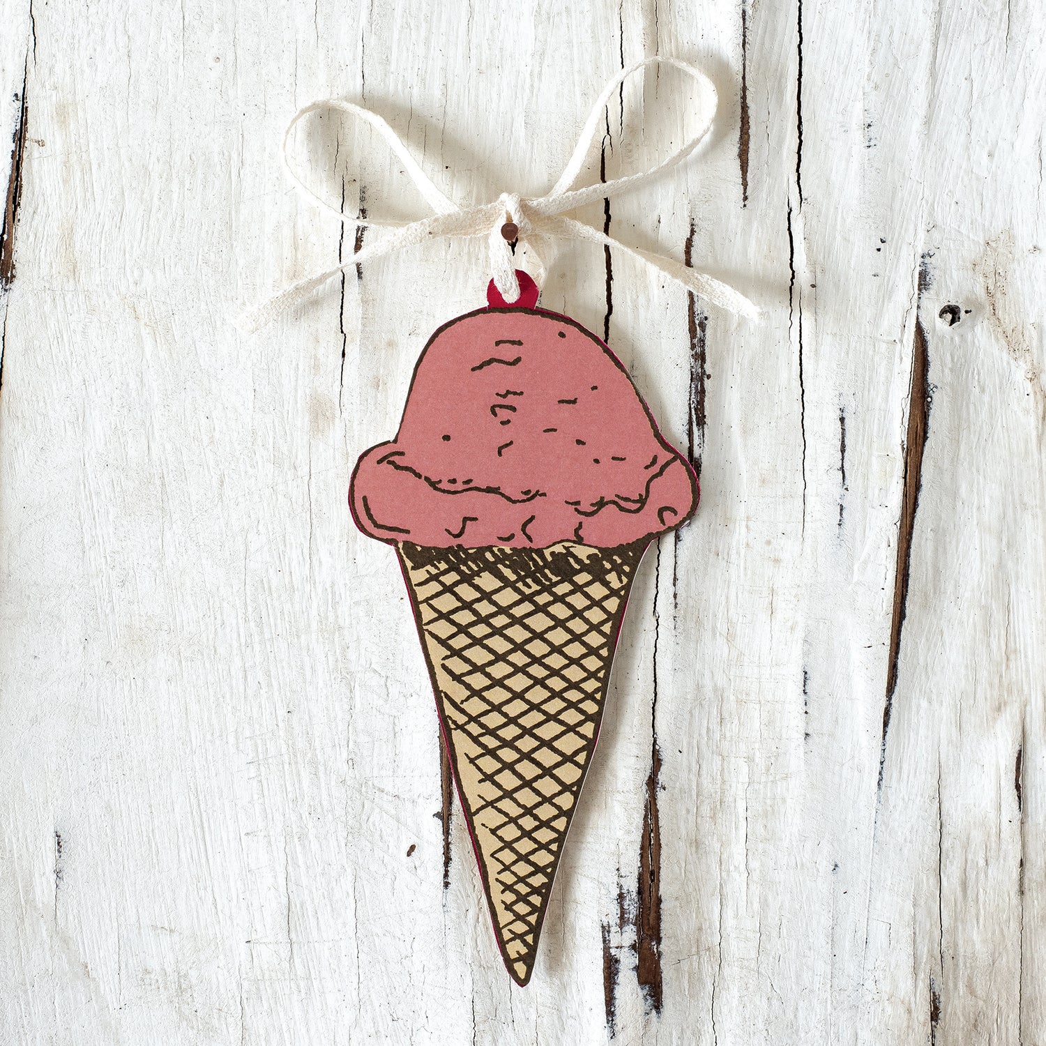 A wooden Ice Cream Cone Gift Tag ornament, made in the USA and created by Hester &amp; Cook, hanging on a white rustic background.