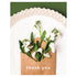 A photo of an open tan kraft paper envelope with delicate white blooms sprouting from it, resting on a white plate on a green table, with "thank you" printed in white on the envelope.