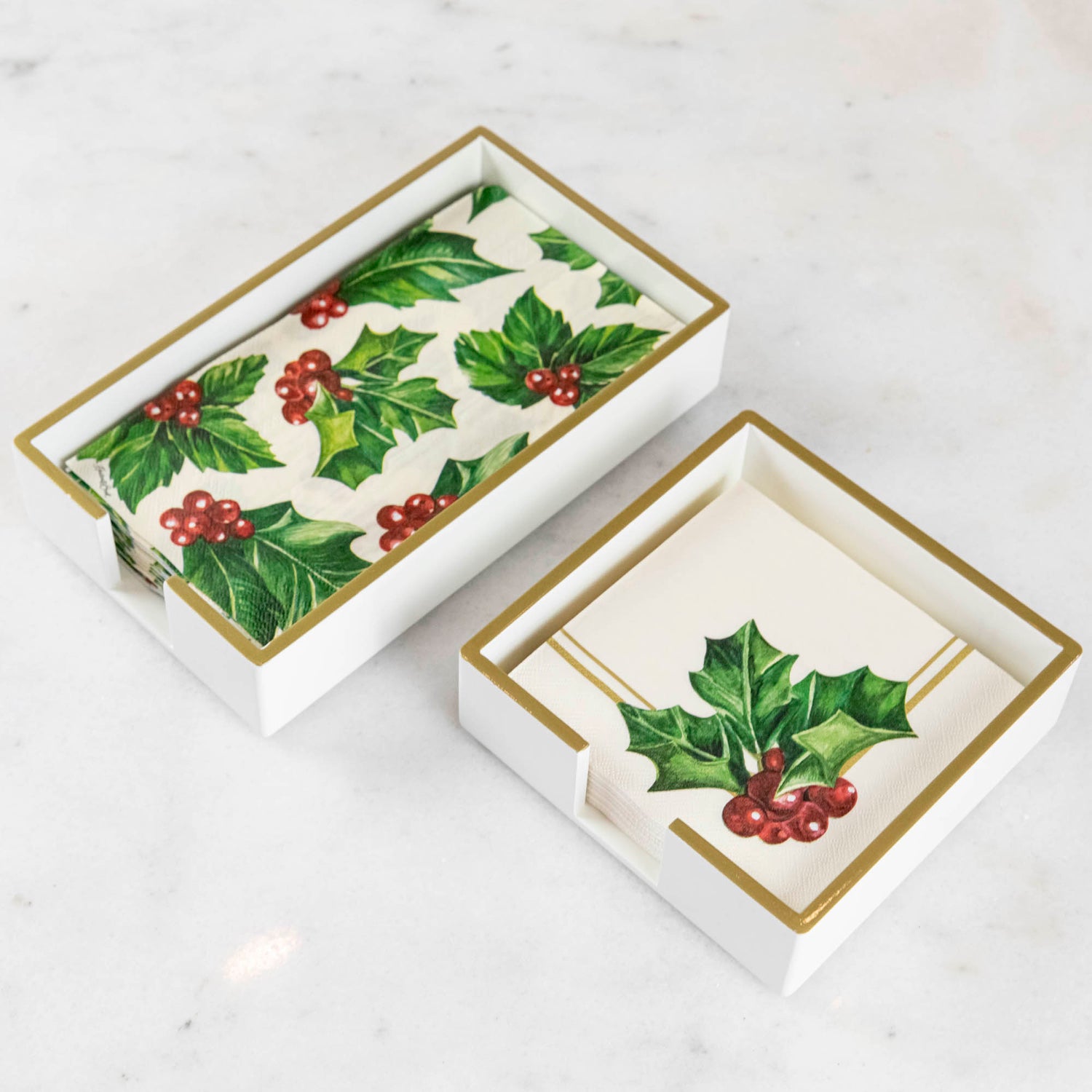 A lacquered wood holder for beverage and guest napkins, featuring a white color with gold trim and a napkin inside.