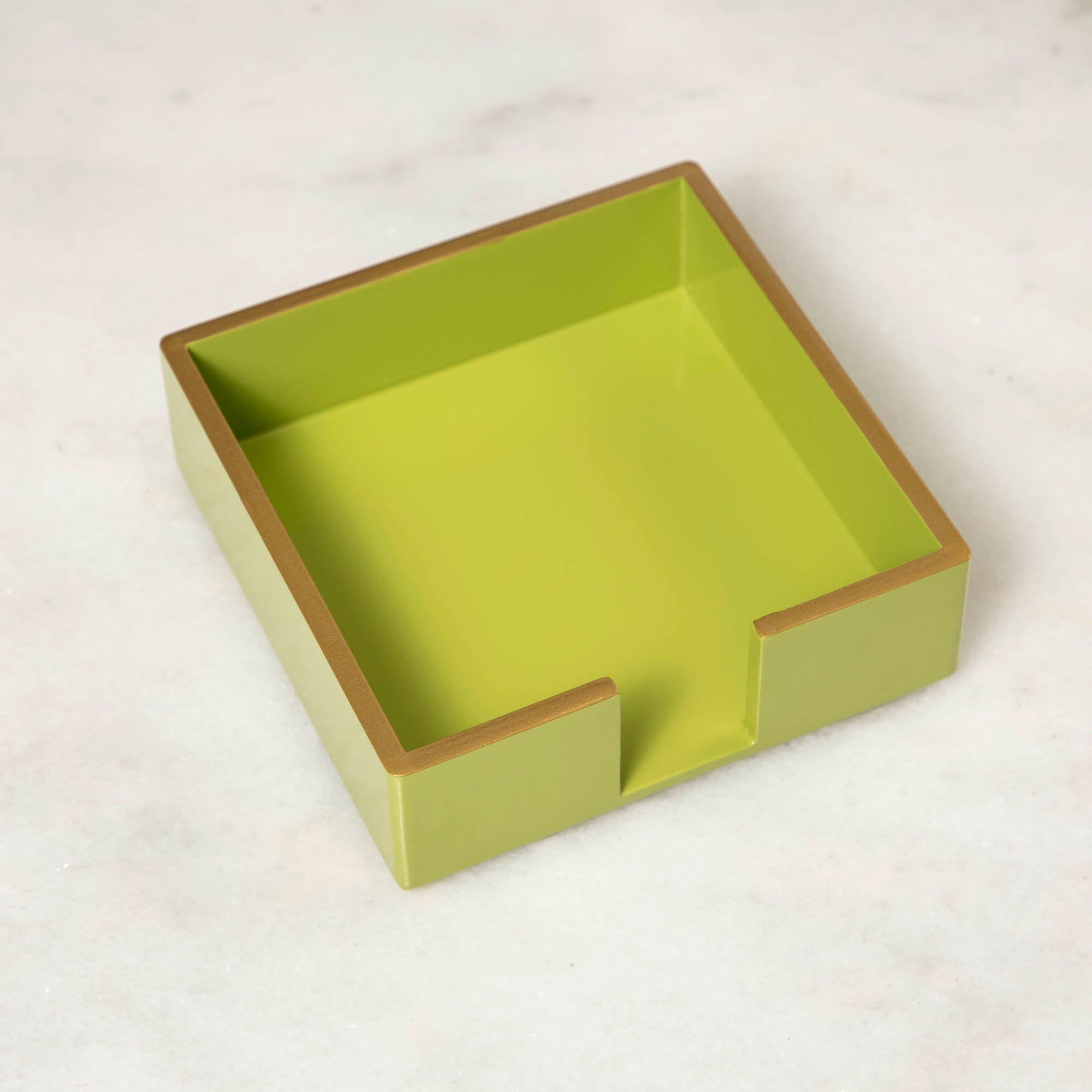 A green lacquered wood beverage napkin caddy with gold trim.