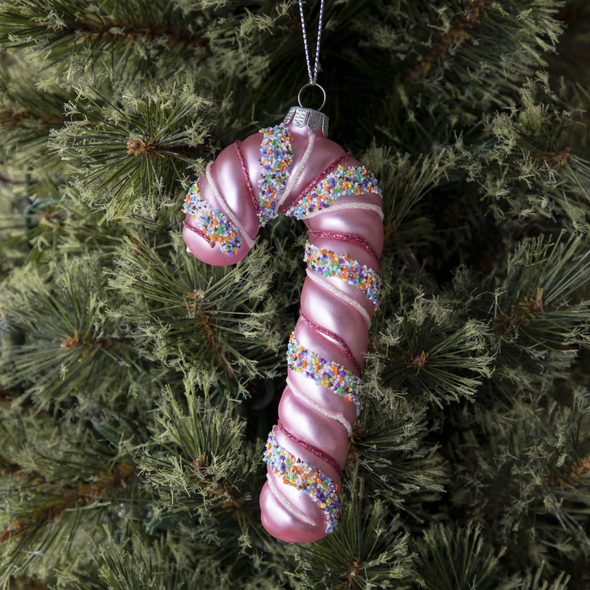 Four festive Glitterville candy cane ornaments on a marble table.