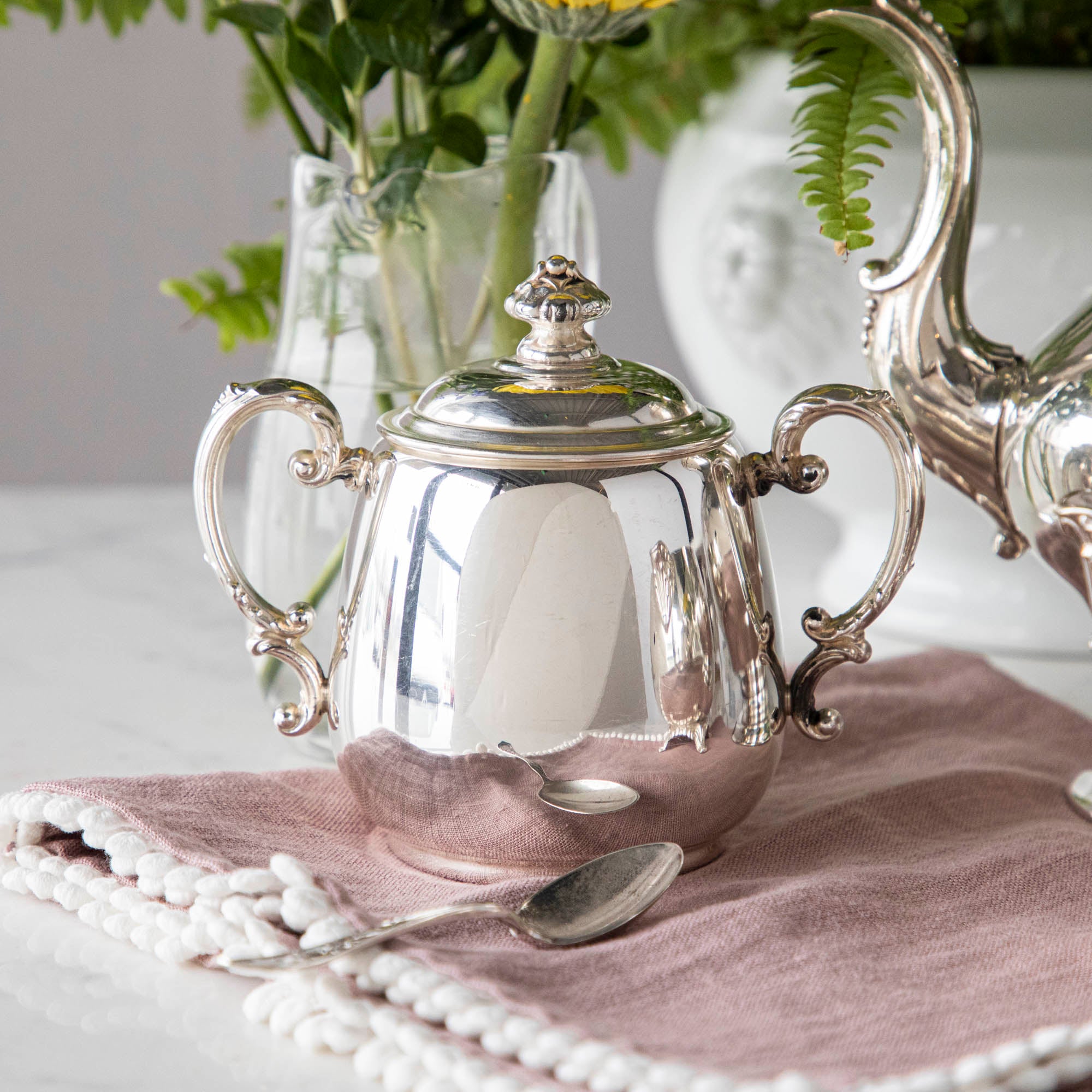 A Hester &amp; Cook vintage silver-plate sugar bowl on a pink tablecloth.