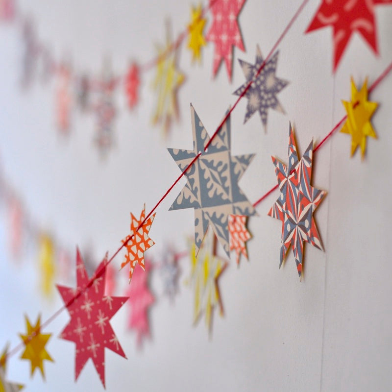 A craft kit titled &quot;Make a Star Garland&quot; by Cambridge Imprint displayed on a shelf with FSC-certified card, star decorations around.