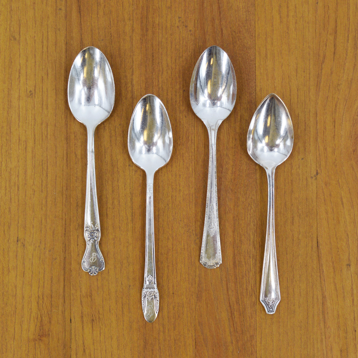 An elegant tea setting with an empty teacup and saucer, a Hester &amp; Cook Vintage Silver-Plate Tea Spoon Set of Four, and a bouquet of fresh flowers on a marble surface.
