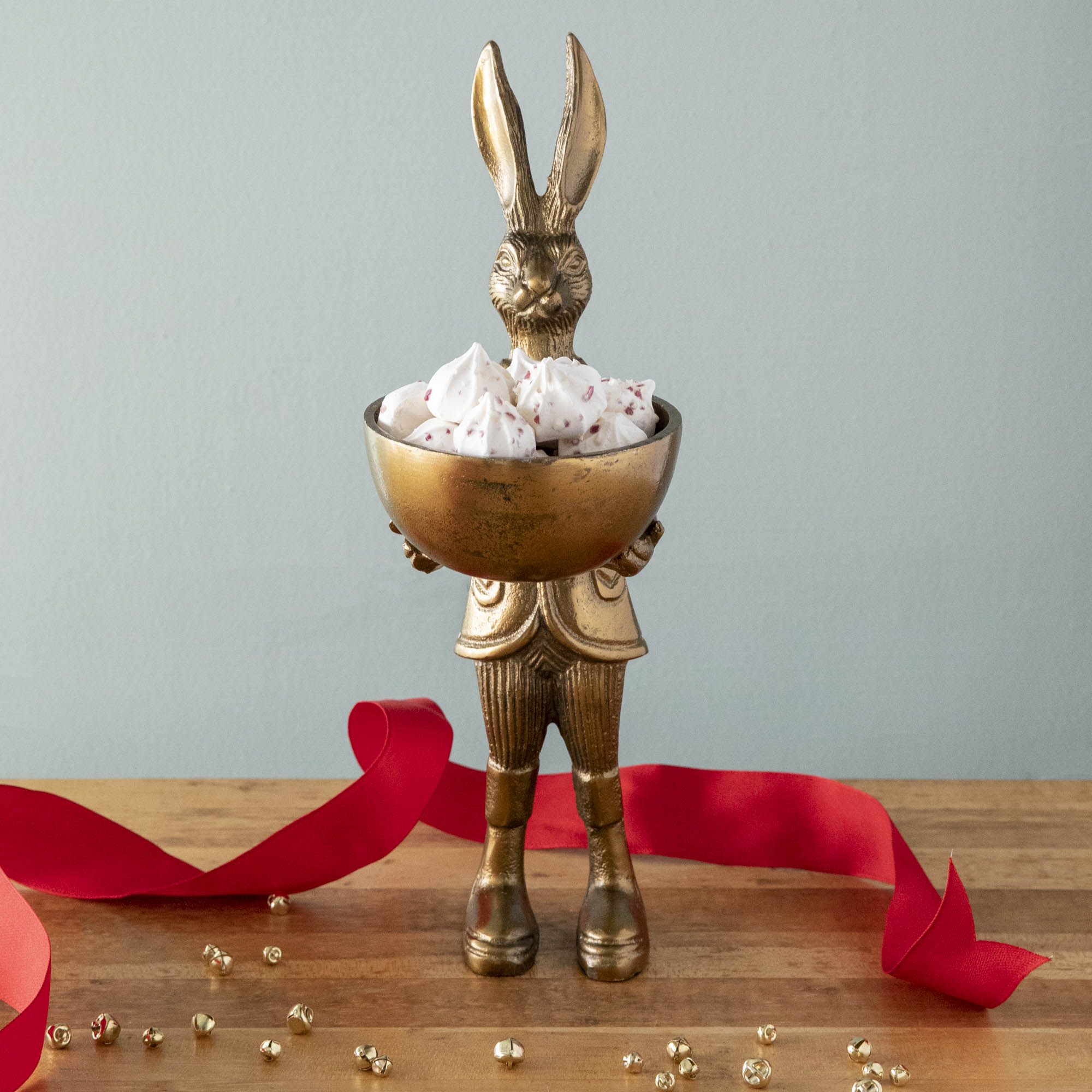 A well-dressed standing Hare Dishstand by Accent Decor holding a round dish of candy on a table.