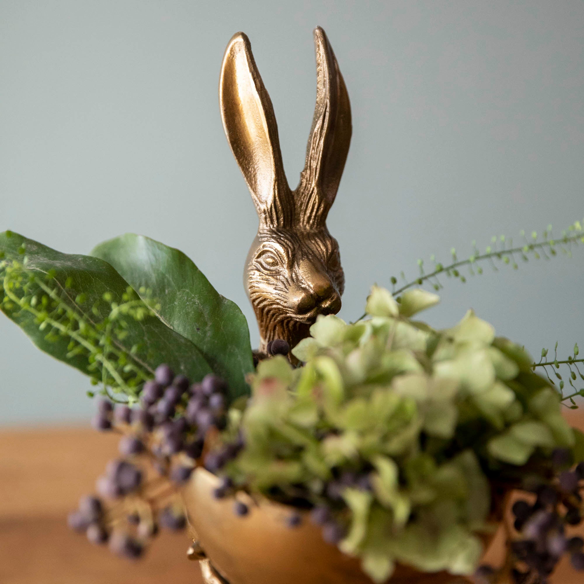 A Hare Dishstand, an Accent Decor decor piece, in a round dish with greens and hydrangeas.