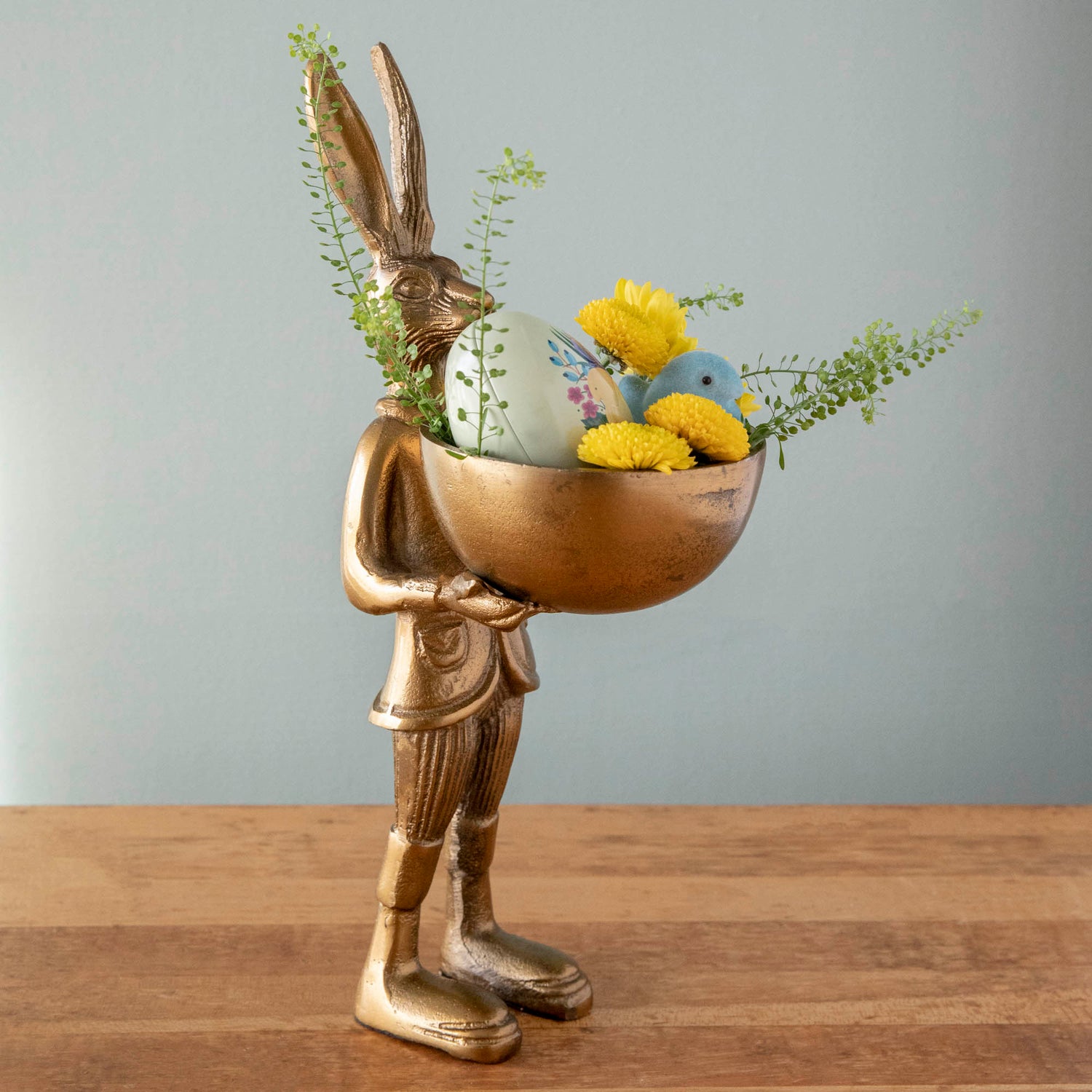 A gold bunny holding an easter basket on an Accent Decor Hare Dishstand.