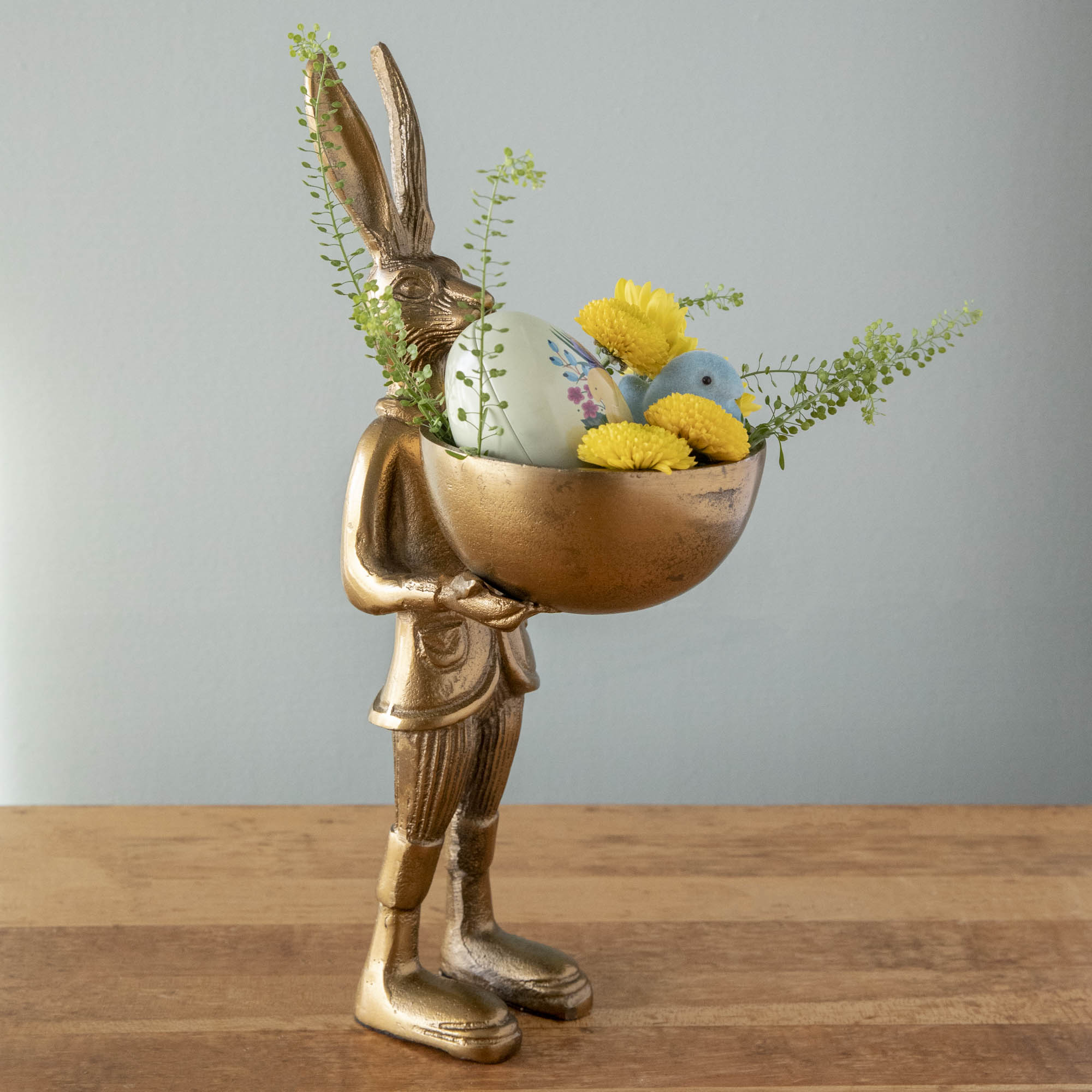 A gold bunny holding an easter basket on an Accent Decor Hare Dishstand.