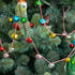 The Vintage Bell Garland of multicolored bells and candy-cane inspired string, strung on a tree.