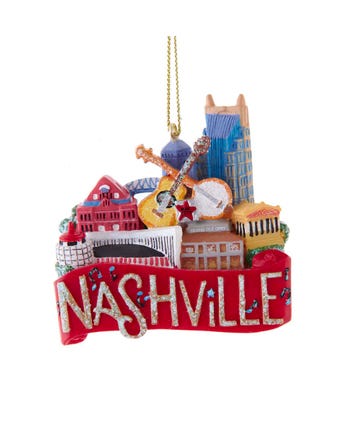 A Christmas ornament featuring a stack of iconic Nashville symbols such as a guitar, a baseball, and buildings, with the word &
