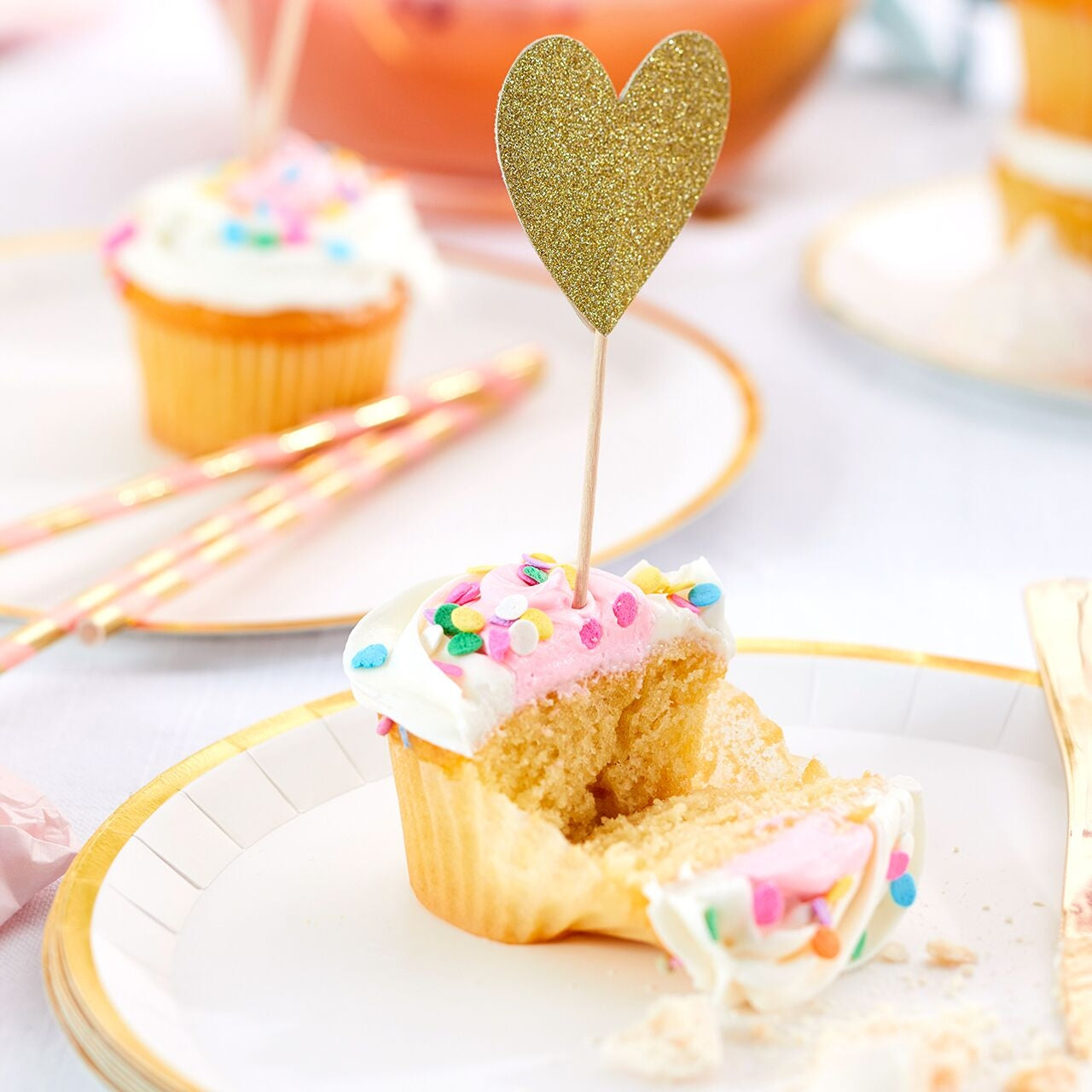A cupcake with a heart-shaped topper on a plate.