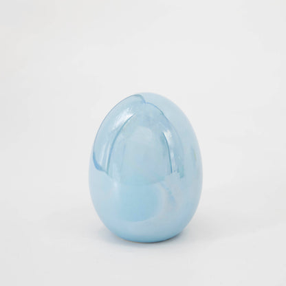 A Glitterville Small Iridescent Egg sitting on a white surface.